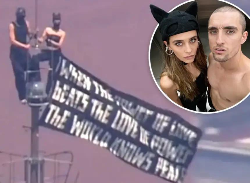Kissing-daredevils scale Empire State Building antenna, hanging flag 1,454 feet over NYC with cringe message