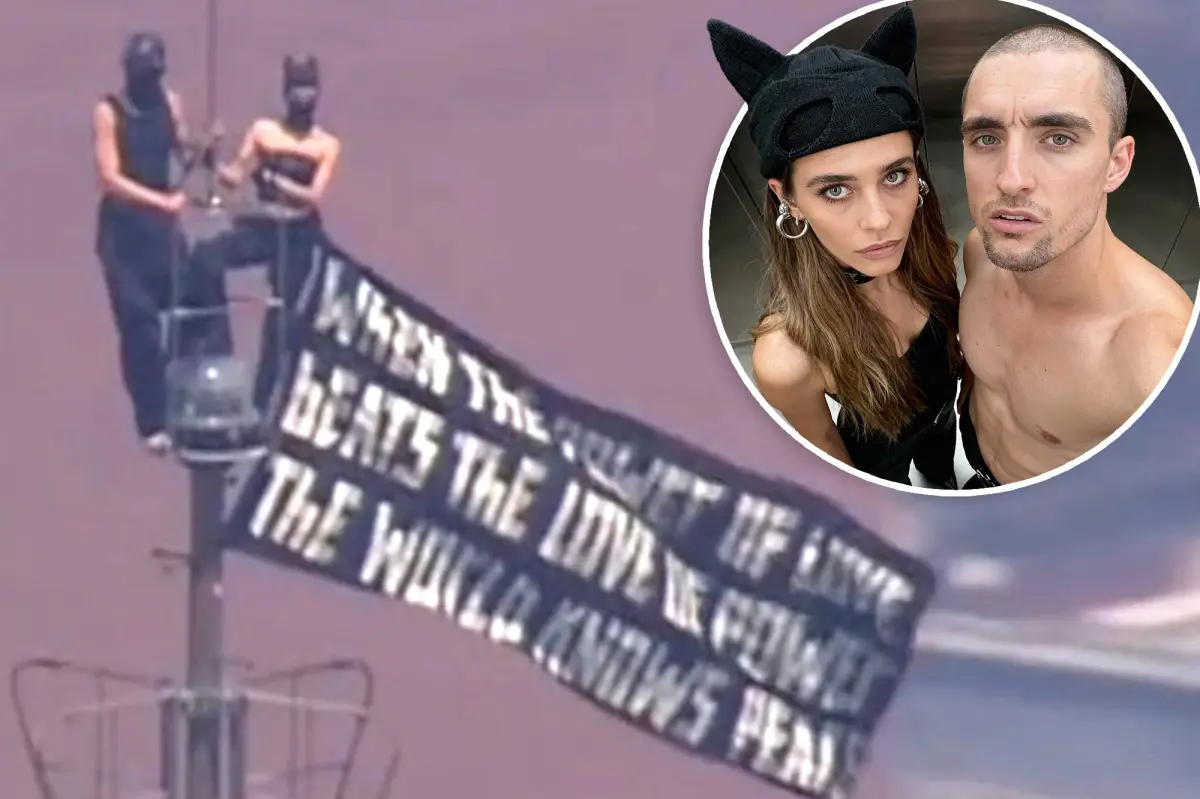 Kissing-daredevils scale Empire State Building antenna, hanging flag 1,454 feet over NYC with cringe message